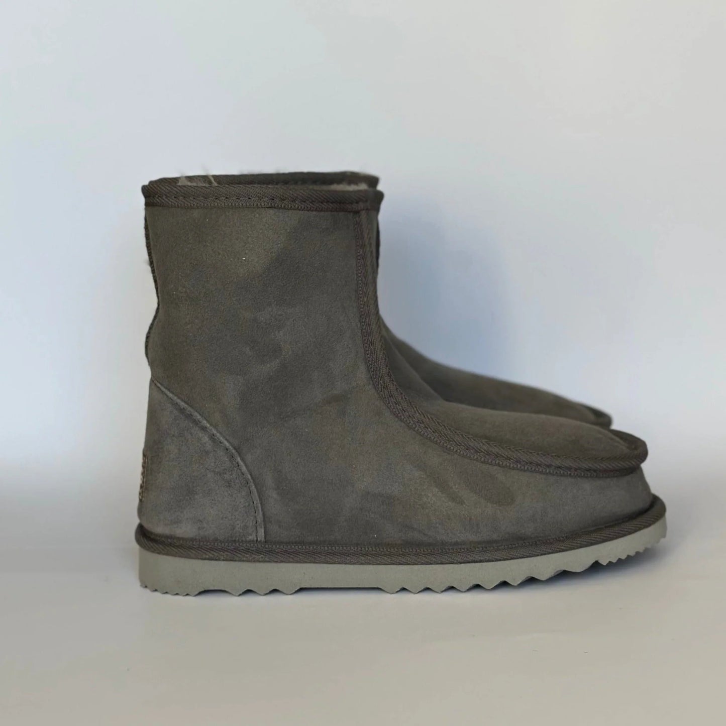 Gray suede ankle boots on a light blue background